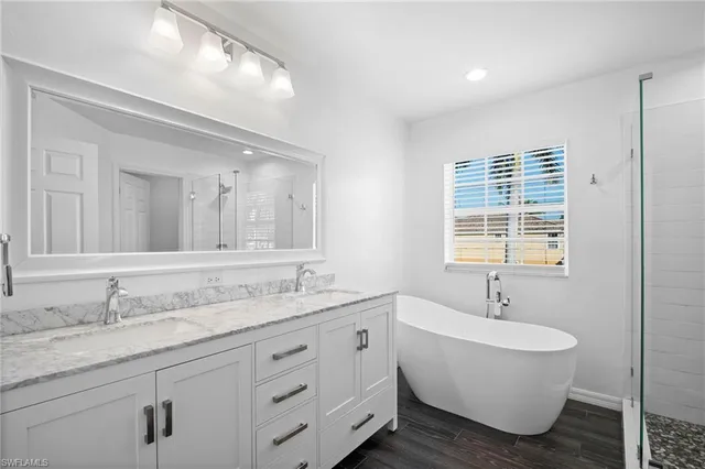 a bathroom with double vanity sinks a mirror and a bathtub