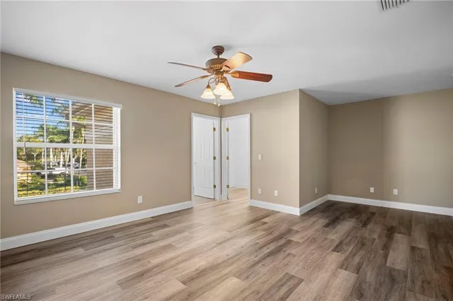 a view of an empty room with window and wooden floor