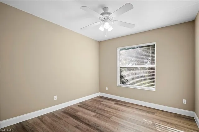 a view of an empty room with a window and wooden floor