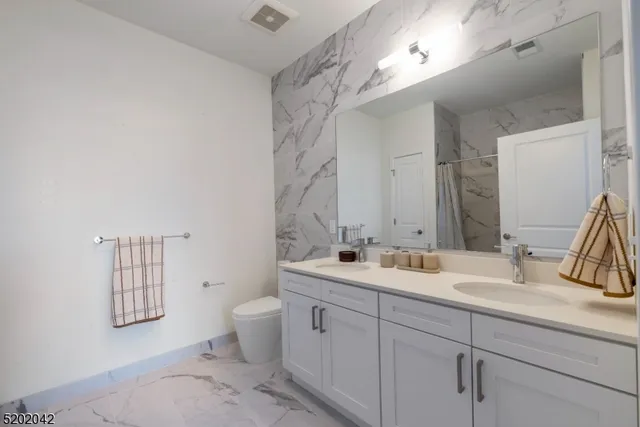 a bathroom with a double vanity sink toilet and a mirror