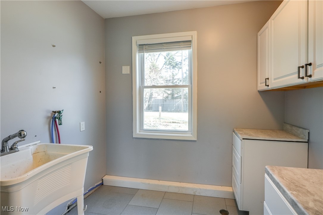 5065 Harper Road Solon, OH 44139 - Photo 18 of 31 Washroom featuring light tile patterned flooring, cabinet space, baseboards, and a sink
