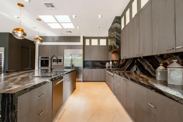 a large kitchen with stainless steel appliances granite countertop a stove a sink and a refrigerator