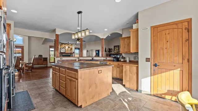 a kitchen with kitchen island granite countertop a refrigerator a stove a oven and a sink with cabinets