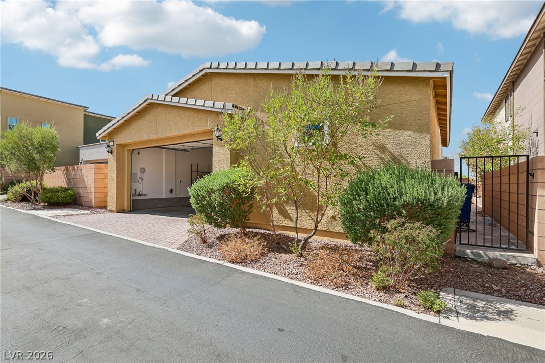 1100 East Sunset Road Henderson, NV 89011 - Photo 47 of 63 An attached garage aligns with the paved driveway, framed by low-maintenance desert landscaping.
