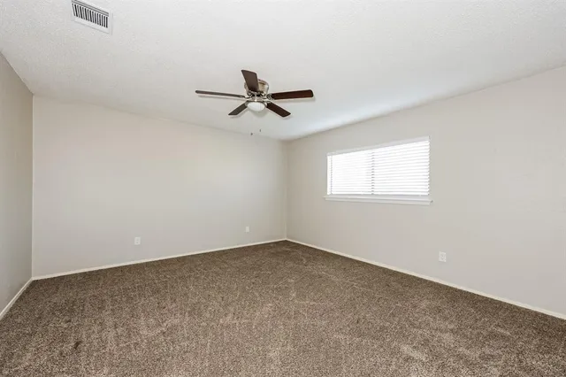 an empty room with a ceiling fan and a window