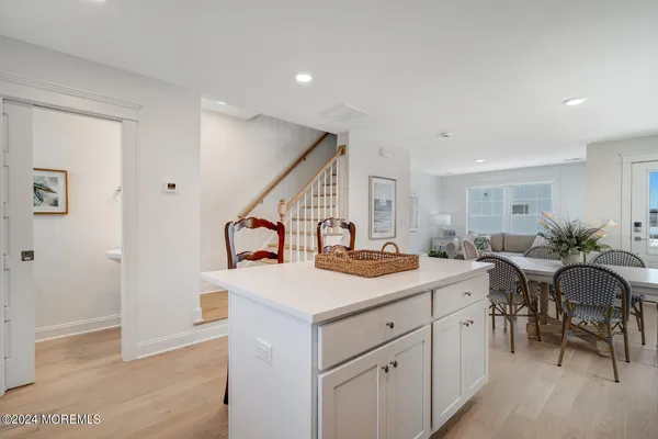 a kitchen with stainless steel appliances kitchen island granite countertop a stove a sink a refrigerator a dining table and chairs with wooden floor