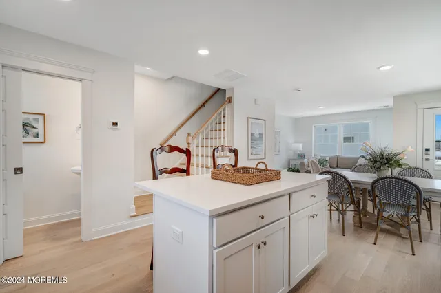 a kitchen with stainless steel appliances kitchen island granite countertop a stove a sink a refrigerator a dining table and chairs with wooden floor