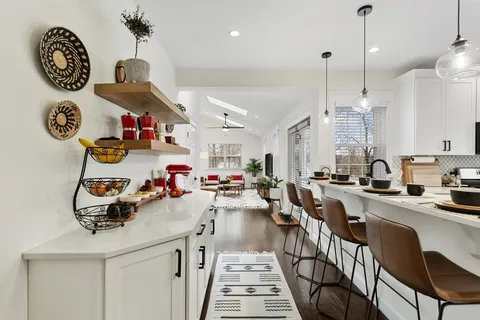 a kitchen with kitchen island granite countertop a stove a sink and a dining table with chairs