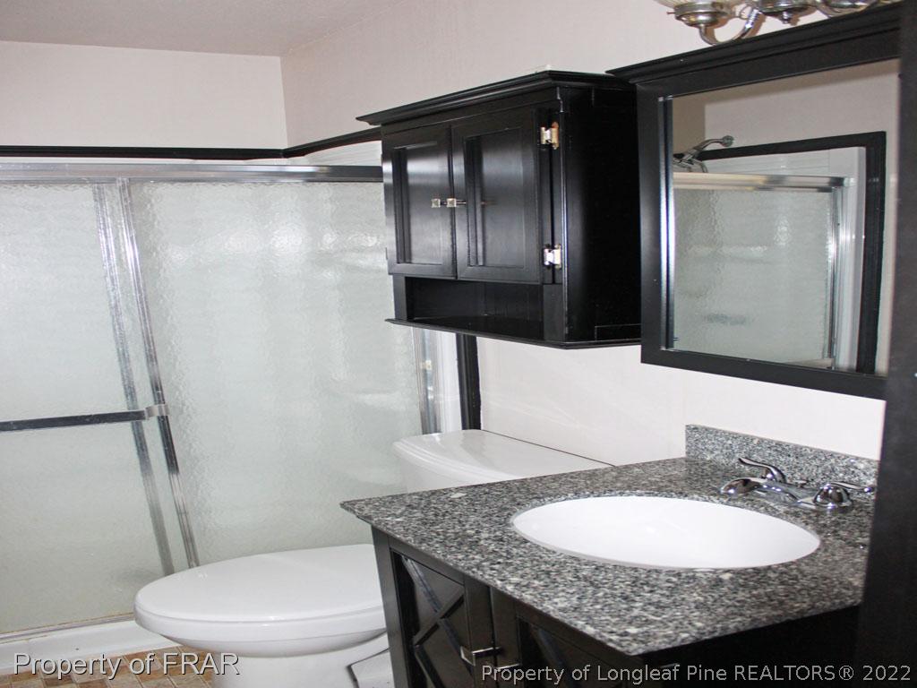 7621 Decatur Drive Fayetteville, NC 28303 - Photo 12 of 15 a bathroom with a granite countertop sink a toilet a mirror and shower