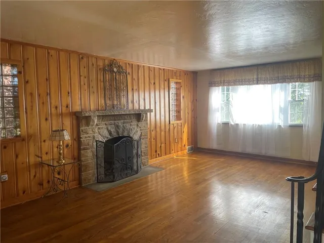 an empty room with wooden floor fireplace and windows