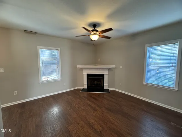 a view of a livingroom with a fireplace a ceiling fan and hardwood floor