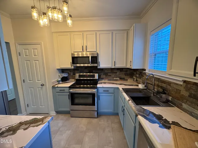 a kitchen with stainless steel appliances a stove a sink a refrigerator and a microwave