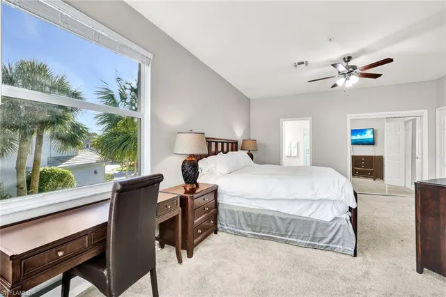 a spacious bedroom with a bed and a flat tv screen on the dresser