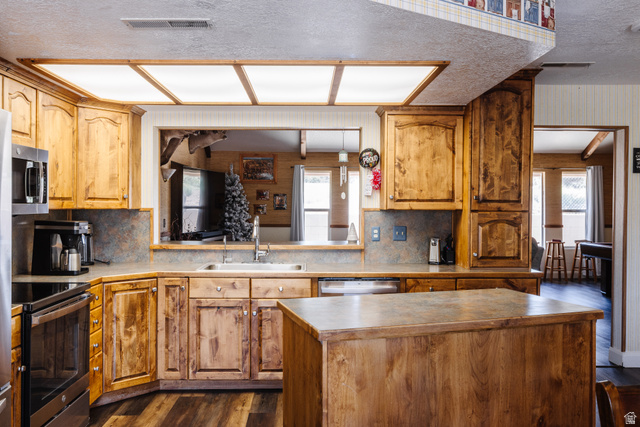 1470 Redwood Tree Street St. George, UT 84790 - Photo 6 of 53 Kitchen featuring wood cabinetry, a center island with a solid surface countertop, stainless steel appliances, and wood-finish flooring