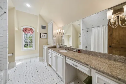 a bathroom with a granite countertop double vanity sink a mirror and a bathtub
