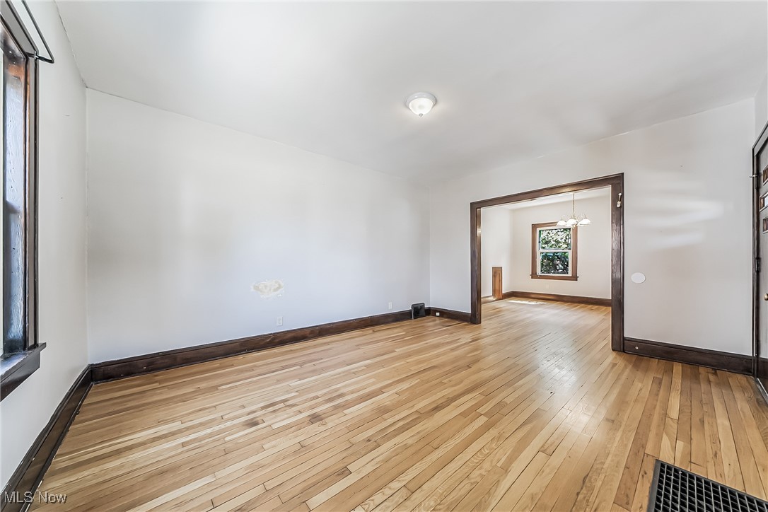Empty room with a notable chandelier and light hardwood / wood-style flooring