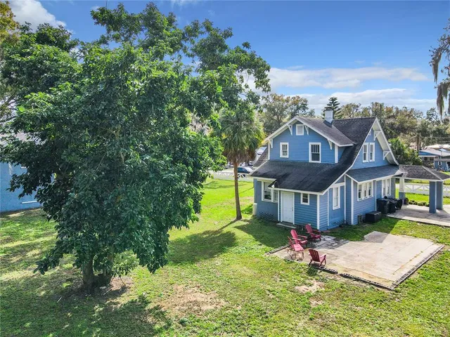 a view of a house with a big yard plants and large tree