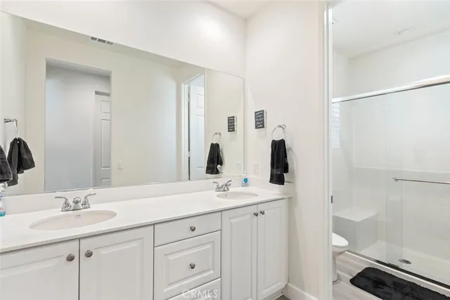 a bathroom with a double vanity sink a toilet and a mirror