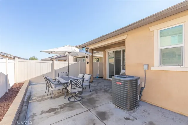 a patio with table and chairs and potted plants
