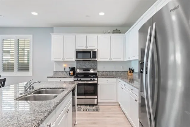 a kitchen with stainless steel appliances granite countertop a sink stove microwave and refrigerator
