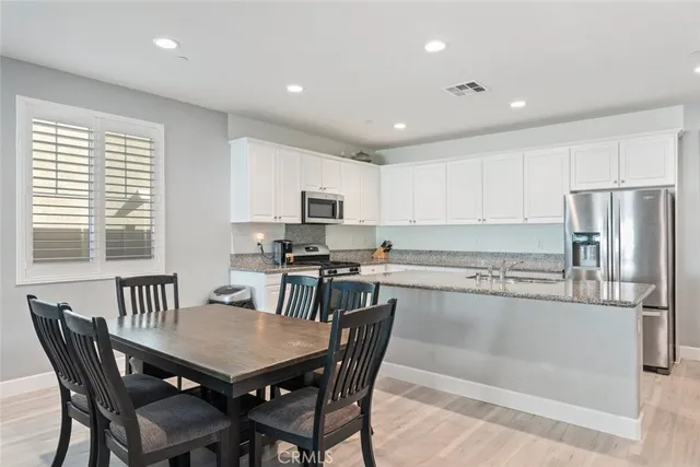 a kitchen with a dining table chairs and refrigerator