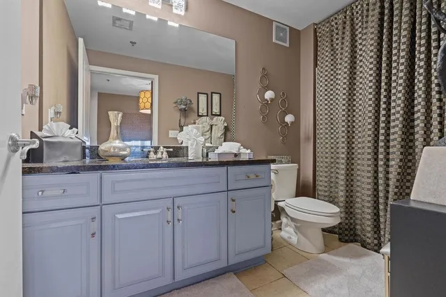 a bathroom with a granite countertop sink toilet and mirror