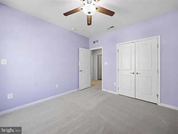 an empty room with chandelier fan and windows