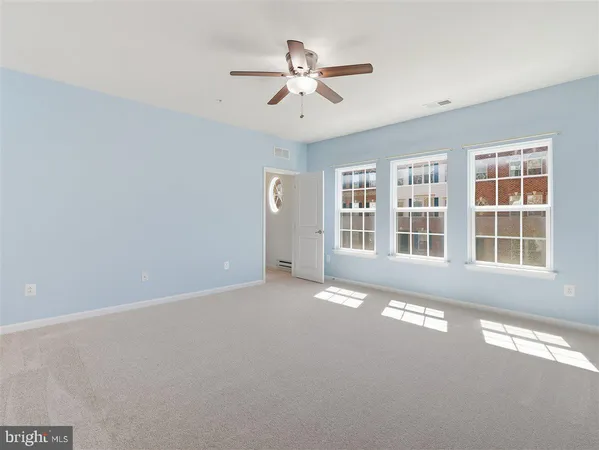 an empty room with windows and ceiling fan