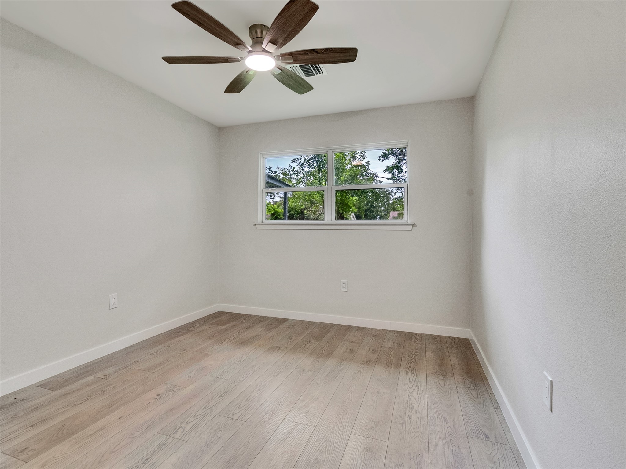 10315 Winding Trail Road La Porte, TX 77571 - Photo 14 of 24 Discover Bedroom #1, a serene retreat featuring elegant luxury vinyl plank flooring, abundant natural light from large windows, and a stylish ceiling fan for comfort and style.