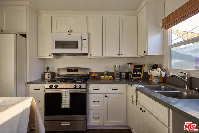 a kitchen with stainless steel appliances granite countertop white cabinets a sink a stove a refrigerator and white cabinets