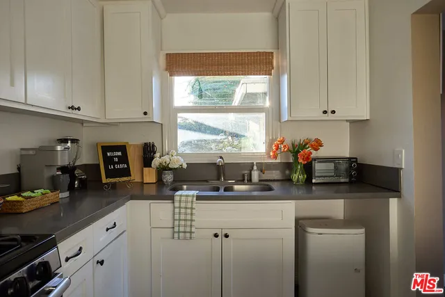 a kitchen with stainless steel appliances granite countertop a sink a stove and white cabinets