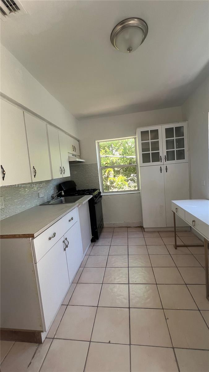 413 Northwest 33rd Street, Unit B Miami, FL 33127 - Photo 4 of 13 a kitchen with a stove a sink and a refrigerator