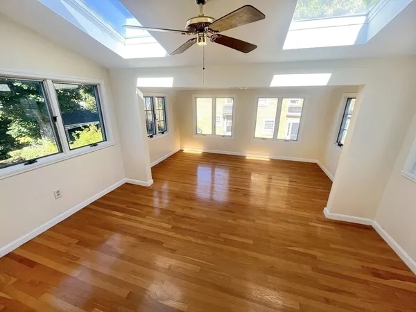 a view of empty room with wooden floor and fan