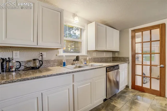 a kitchen with granite countertop a sink window and cabinets