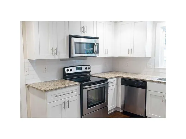 a kitchen with stainless steel appliances granite countertop a stove a sink and a microwave