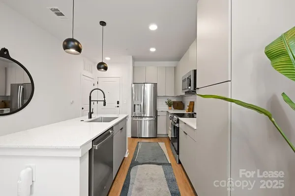 a kitchen with stainless steel appliances granite countertop a sink a stove a refrigerator and island