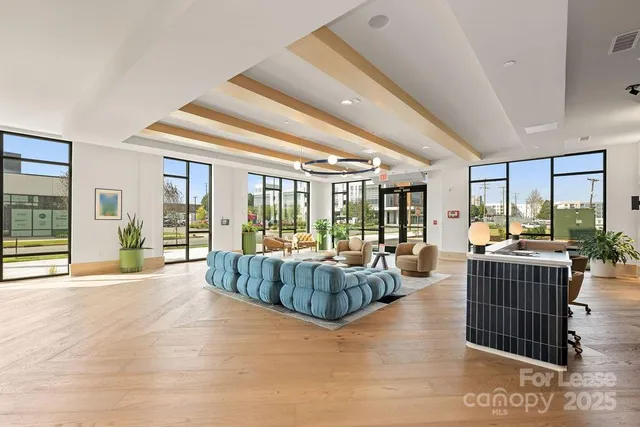 a living room with furniture large windows and wooden floor