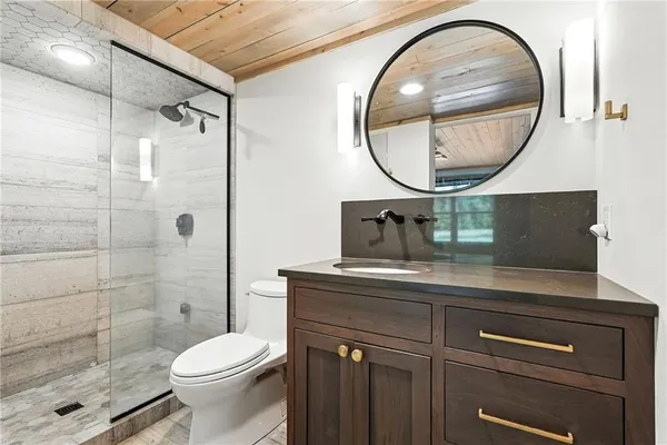 a bathroom with a sink a mirror a toilet and a shower