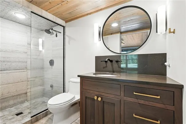 a bathroom with a sink a mirror a toilet and a shower