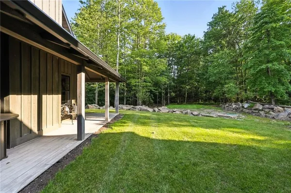 a view of swimming pool with lawn chairs and large trees