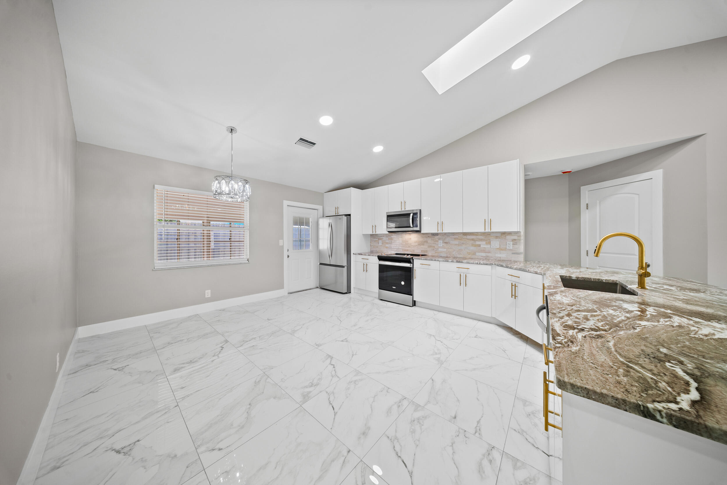 1627 Southeast Monroe Street Stuart, FL 34997 - Photo 10 of 33 a large white kitchen with kitchen island a sink stainless steel appliances and cabinets
