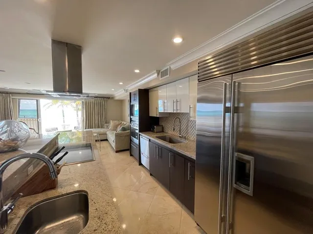 a large kitchen with stainless steel appliances kitchen island granite countertop a refrigerator and a stove top oven