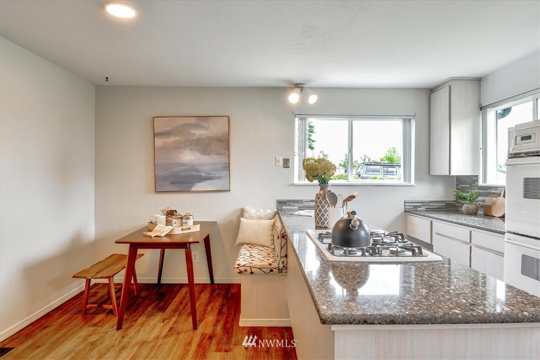5202 Northeast 3rd Street Renton, WA 98059 - Photo 10 of 27 a kitchen with a stove a sink a dining table and chairs with wooden floor