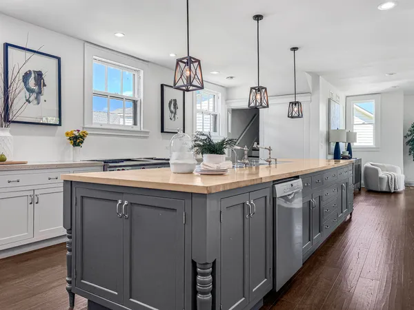 a kitchen with kitchen island granite countertop a stove a sink and a wooden floors