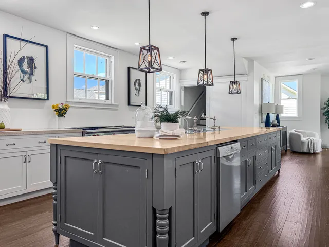 a kitchen with kitchen island granite countertop a stove a sink and a wooden floors