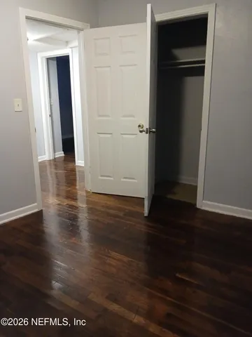an empty room with wooden floor & closet