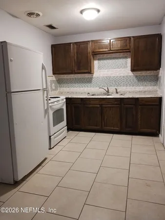 a kitchen with granite countertop a stove a sink and a refrigerator