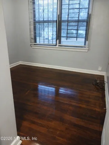 a view of empty room with window and wooden floor