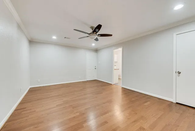 an empty room with wooden floor and ceiling fan