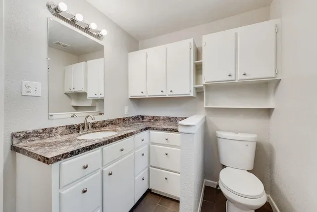 a bathroom with a granite countertop toilet sink and mirror